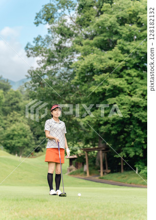A golfer woman playing golf at a golf course (smile, tee shot, golf competition) 128182132