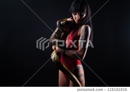 Photo of brunette woman with snake in red lingerie on dark background 128182838