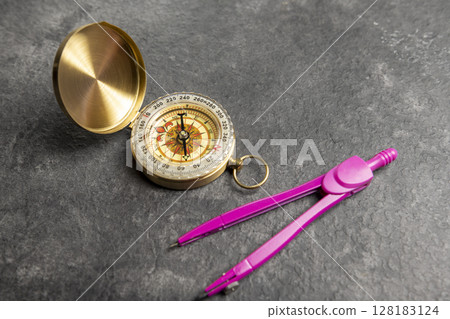 Closeup view of navigational compass and pink compasses on a black background. Travel guidance equipment Closeup view of navigational compass and pink compasses on a black background. Travel guidance equipment 128183124