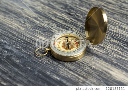 Closeup view of navigational compass on wooden background. Travel guidance equipment 128183131