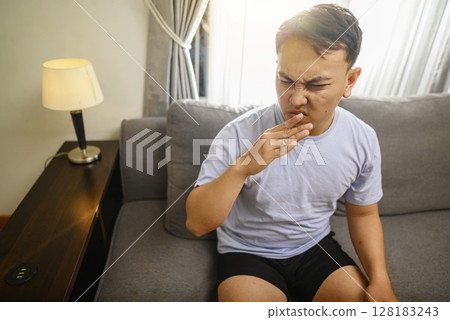Indonesian southeast asian man holding his breath with his fingers on his nose after smelling something stinky and disgusting, an intolerable smell in the house Indonesian southeast asian man holding his breath with his fingers on his nose after smelling something stinky and disgusting, an intolerable smell in the house 128183243