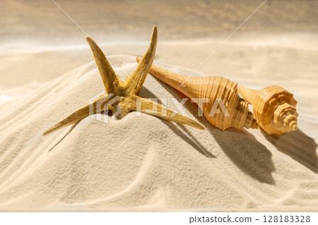 Starfish and seashells on the sand with a wooden background. Beach scene. Summer concept Starfish and seashells on the sand with a wooden background. Beach scene. Summer concept 128183328