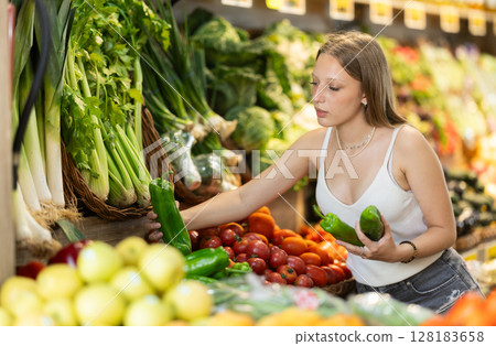 Woman near vegetable stand in store choose bell pepper Woman near vegetable stand in store choose bell pepper 128183658