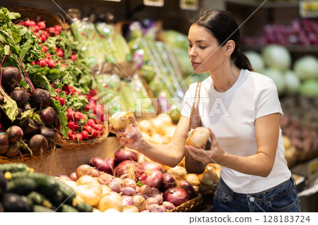 Young woman choosing onions in the vegetable department Young woman choosing onions in the vegetable department 128183724