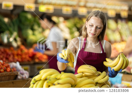 Woman seller putting bananas on the counter Woman seller putting bananas on the counter 128183806