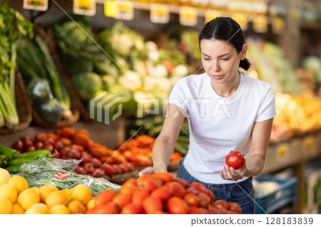 Young woman choosing red tomatoes 128183839
