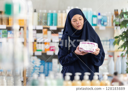 Young Muslim woman in summer clothes choosing feminine pads in chemistry 128183889