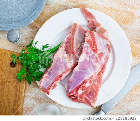 Fresh pork ribs on white ceramic plate with parsley on table 128183922