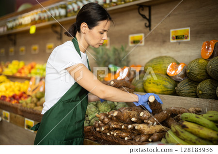 Female seller laying out tapioca root on the counter Female seller laying out tapioca root on the counter 128183936