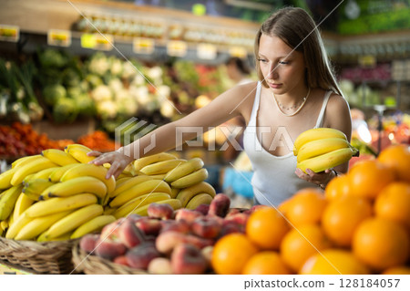 Blonde woman near the banana counter in the store Blonde woman near the banana counter in the store 128184057