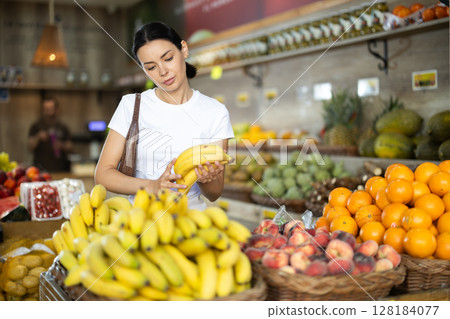 Adult woman choosing bananas at vegetable shop 128184077