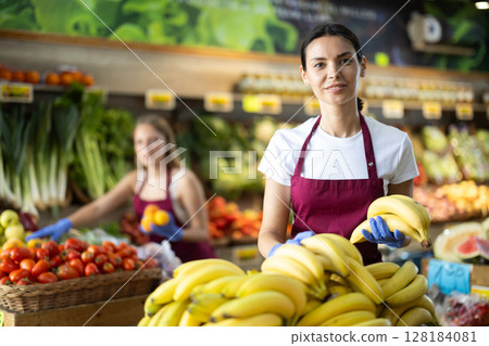 Woman seller putting bananas on the counter 128184081