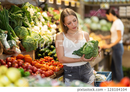 Woman choosing green cabbage in grocery store 128184104