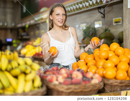 Woman near vegetable stand in store choose orange 128184206