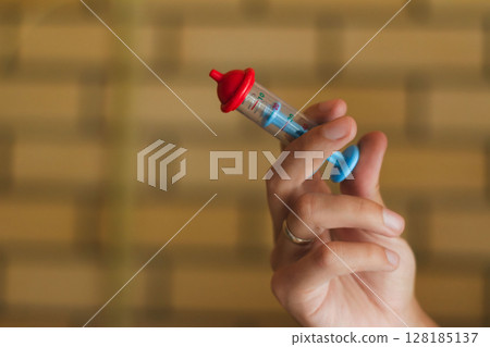 A Hand Gripping a Brightly Colored Syringe Intended for Playful Activities or Educational Purposes A Hand Gripping a Brightly Colored Syringe Intended for Playful Activities or Educational Purposes 128185137