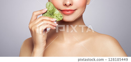 Young woman doing scrapping massage facial skin 128185449