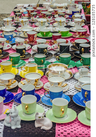 Colorful vintage porcelain teacups and saucers displayed on market table. High quality photo Colorful vintage porcelain teacups and saucers displayed on market table. High quality photo 128185735