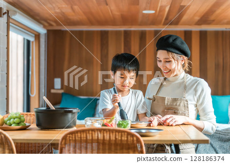 Family preparing meals in a bungalow/cottage, cooking for parents and children (family trip/glamping) 128186374