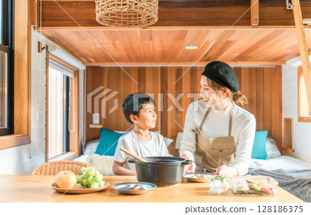 Family enjoying cooking together, preparing meals and serving curry at a cottage (family trip/glamping) 128186375