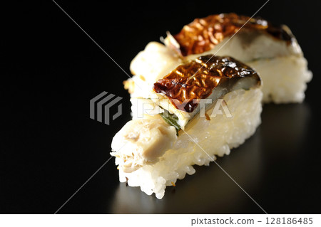 Grilled mackerel sushi photographed against a black background 128186485