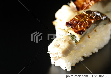 Grilled mackerel sushi photographed against a black background 128186488