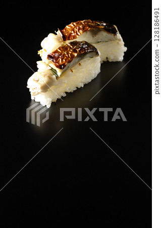 Grilled mackerel sushi photographed against a black background 128186491