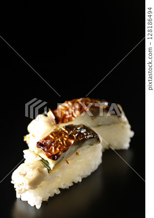 Grilled mackerel sushi photographed against a black background 128186494