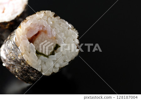 Nori rolls with plum, shiso and yam photographed against a black background Nori rolls with plum, shiso and yam photographed against a black background 128187004
