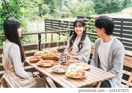 Group of young Asian men and women eating on wooden deck, balcony 128187055