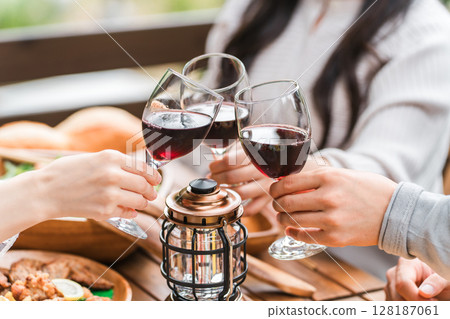 Hands of a young group of men and women toasting at a home party/glamping on a wooden deck 128187061