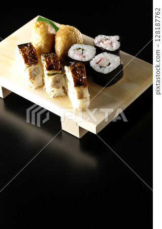 Grilled mackerel, norimaki, and inari sushi photographed against a black background Grilled mackerel, norimaki, and inari sushi photographed against a black background 128187762