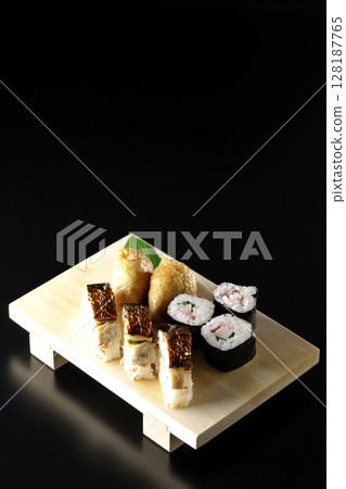 Grilled mackerel, norimaki, and inari sushi photographed against a black background Grilled mackerel, norimaki, and inari sushi photographed against a black background 128187765