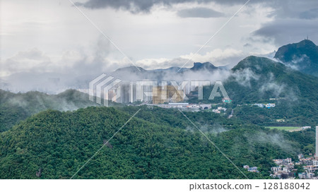 July 1 2025 View of a Foggy Cityscape Amid Green Hills and Moody Skies 128188042