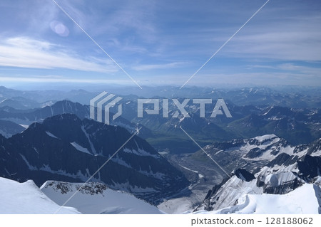 Tranquil Lake With Lush Green Forest, Snow-Capped Mountain, Blue Sky And White Clouds 128188062