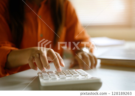 Close up of woman using a calculator, working on financial or accounting tasks 128189263