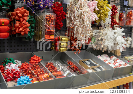 Vibrant gift bows and colorful curling ribbons neatly displayed on retail shelves, offering a festive selection for holiday celebrations and present wrapping Vibrant gift bows and colorful curling ribbons neatly displayed on retail shelves, offering a festive selection for holiday celebrations and present wrapping 128189324