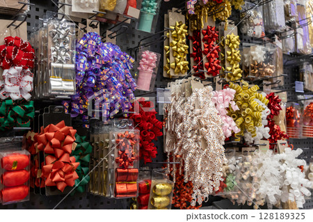 Vibrant collection of festive gift bows and decorative ribbons beautifully displayed in a retail store aisle, perfect for holiday celebrations and special occasions Vibrant collection of festive gift bows and decorative ribbons beautifully displayed in a retail store aisle, perfect for holiday celebrations and special occasions 128189325