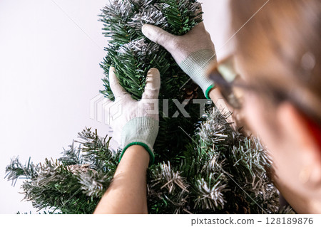 assembling artificial christmas tree branches with gloves, preparing frosted tree for storage or holiday decoration 128189876