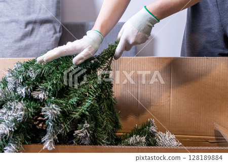 assembling artificial christmas tree from cardboard box in preparation for holiday decoration 128189884