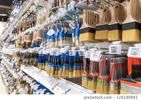 wide selection of paintbrushes on display in a hardware store aisle with colorful handles and price tags wide selection of paintbrushes on display in a hardware store aisle with colorful handles and price tags 128189891