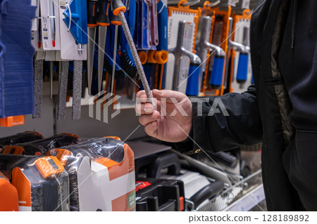 man holding a diamond-coated file in a hardware store aisle with various tools on display man holding a diamond-coated file in a hardware store aisle with various tools on display 128189892