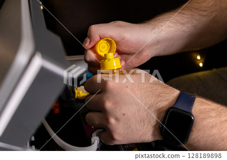 opening yellow ink bottle during printer refill process with a focus on preparation for tank filling opening yellow ink bottle during printer refill process with a focus on preparation for tank filling 128189898