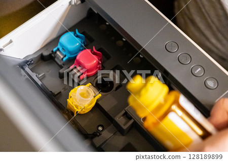 refilling ink tank in printer with focus on color cartridge compartments and yellow bottle refilling ink tank in printer with focus on color cartridge compartments and yellow bottle 128189899