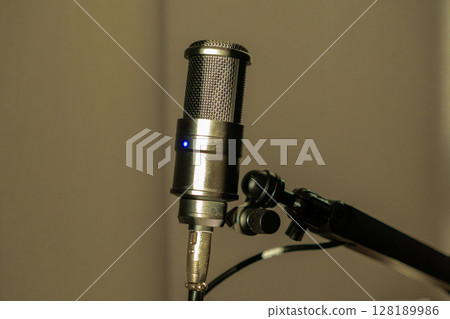 Professional studio microphone on an adjustable stand with warm ambient lighting 128189986