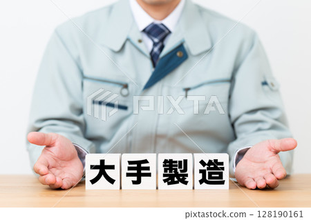 A middle-aged male businessman wearing work clothes and a block of a major manufacturing company 128190161