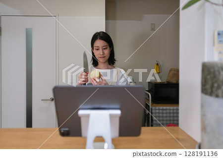 A woman cooking in the kitchen while looking at a tablet 128191136