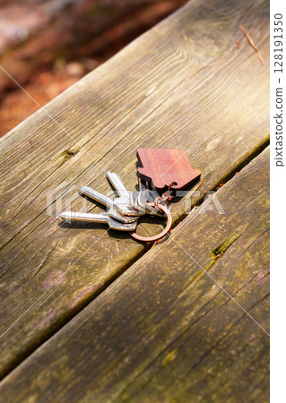 Bunch of keys thrown on wooden antique table with house shaped keychain 128191350