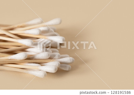 Wooden ecological cotton swab on beige background. Zero waste, sustainable resources. Close up. Wooden ecological cotton swab on beige background. Zero waste, sustainable resources. Close up. 128191586