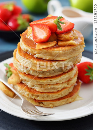 pancakes topped with apple slices and strawberries 128191700