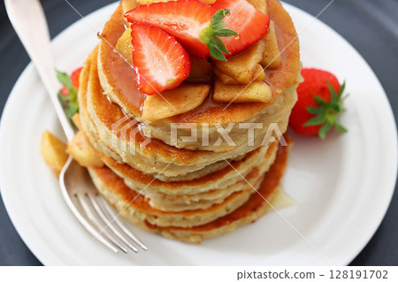 pancakes topped with apple slices and strawberries 128191702